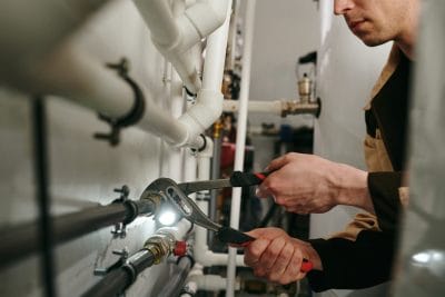 Technician inspecting commercial plumbing pipes in Glendale